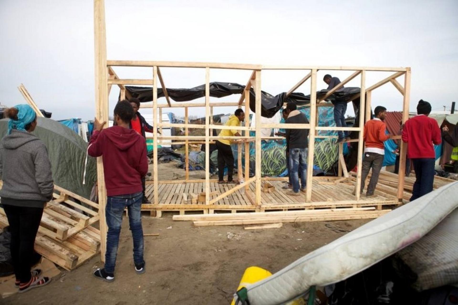 Refugees, volunteers, and NGOs cooperating on the construction of camp facilities at Calais Refugee Camp. | Photo by Building in Calais Jungle