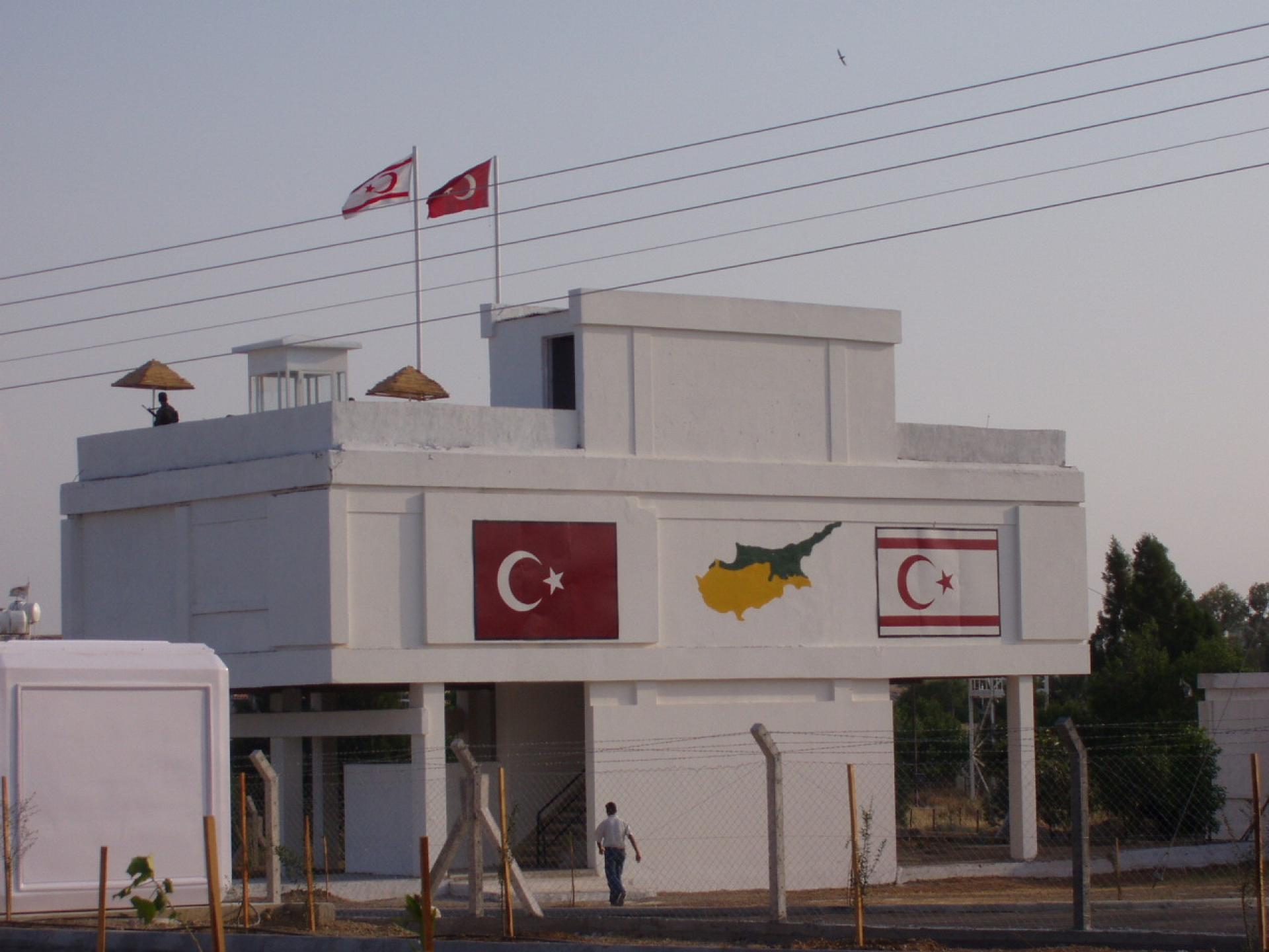 The flags of Turkey and “TRNC” at the north facade of the Agios Dometios with the plan of the divided island placed between them. | Photo by Socrates Stratis