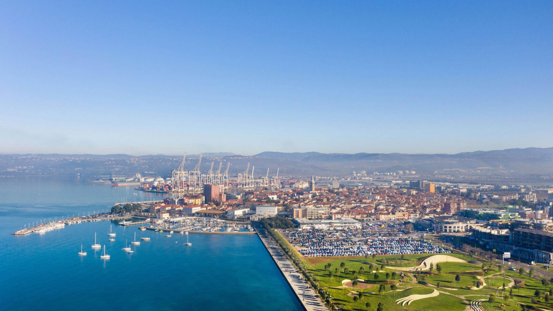 Today’s view on the historical city centre: a new city’s park, parking facilities, an unfinished Solis on the right and the port behind. | Photo © Enota