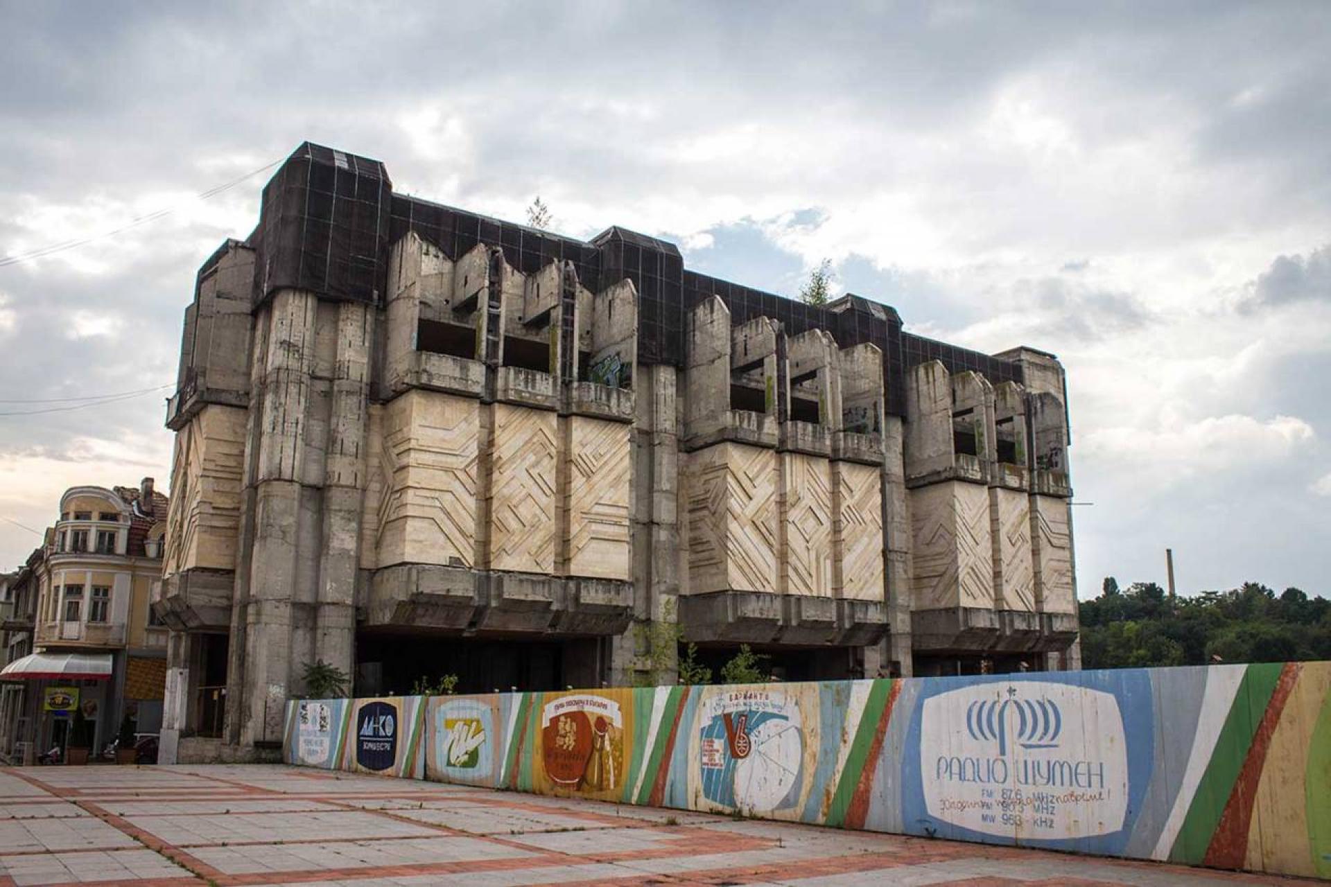 Western block rises behind an advertising fence.| Photo © Darmon Richter