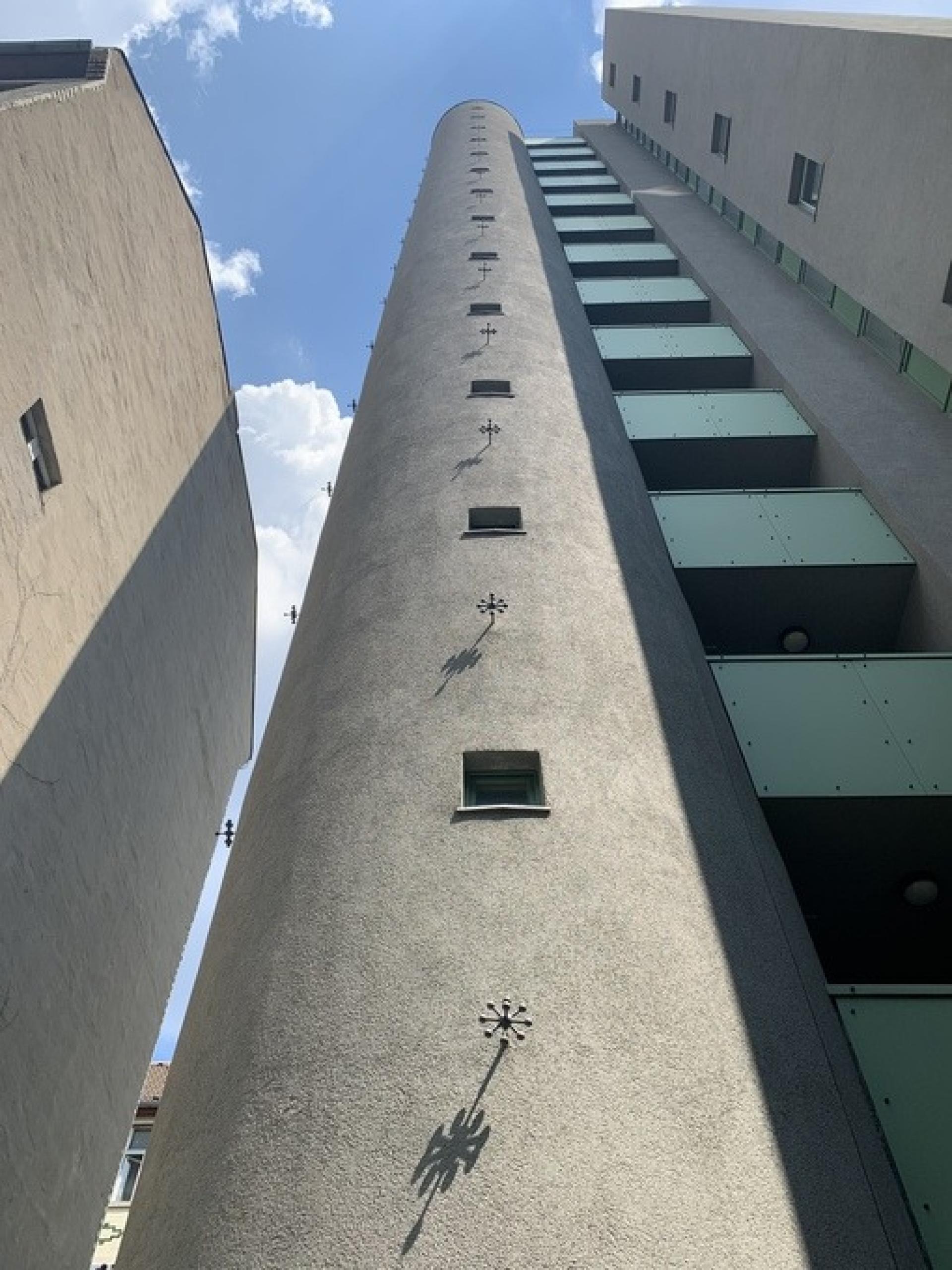 The metallic flowers on the facade of the tower supposed to represent grips for angels to hold onto when they climb the sides of the tower inspired by the 1987 film “Wings of Desire" directed by Wim Wenders.